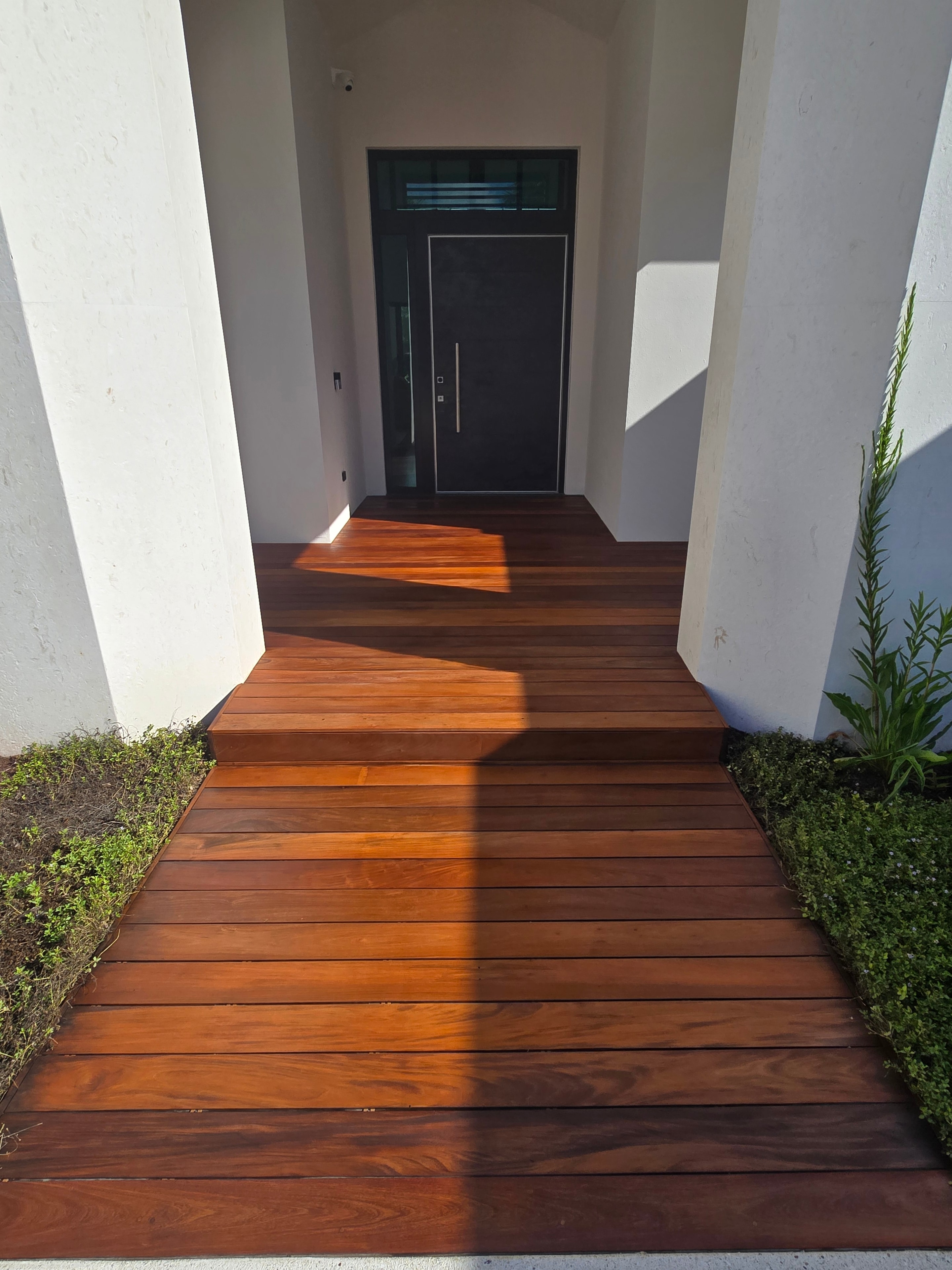 Residential entryway with refinished hardwood deck and black door